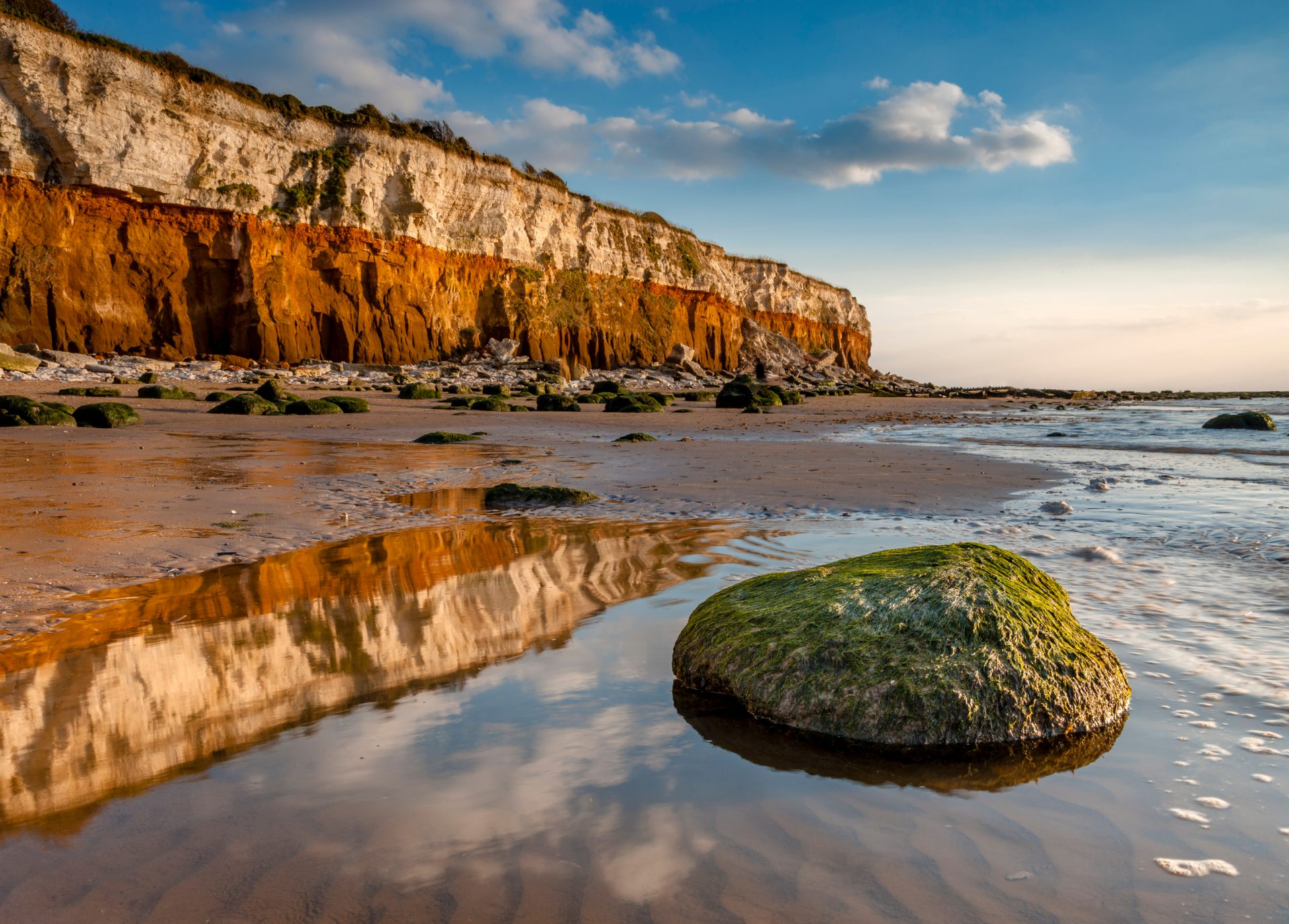 The two tone cliffs at Hunstanton reflected in a pool of water on the beach.